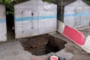 В Омске на улице Перелета провалился асфальт — чтобы устранить яму, придется убрать несколько гаражей и деревьев
