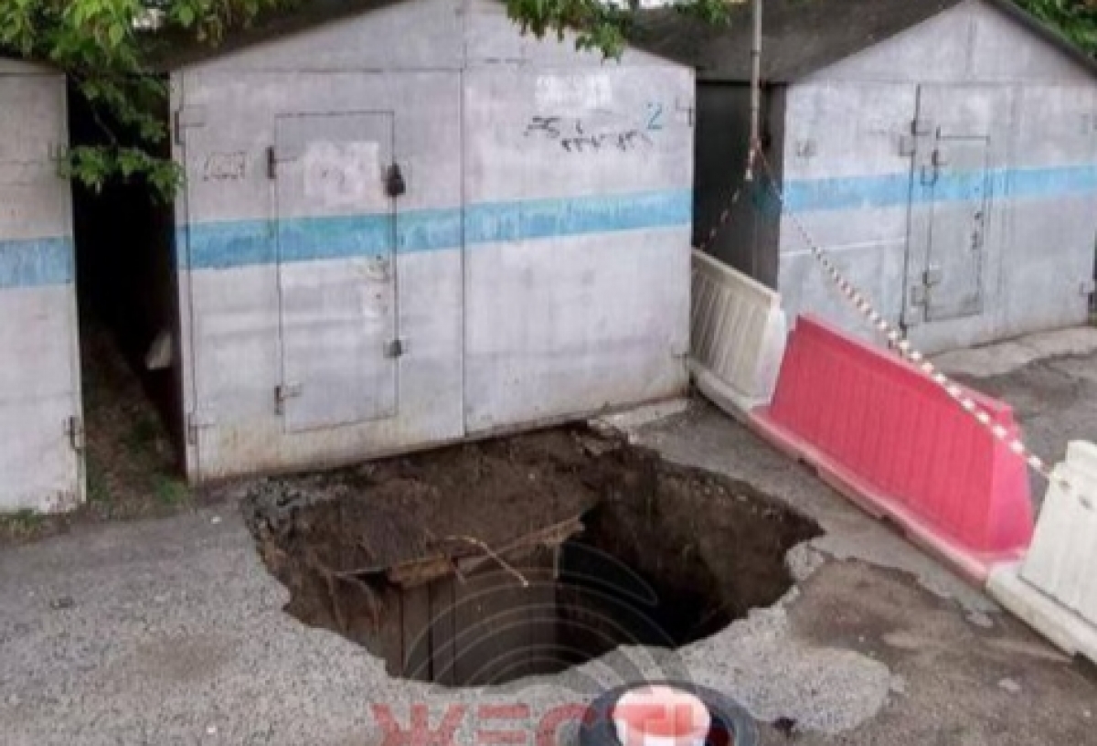 В Омске на улице Перелета провалился асфальт — чтобы устранить яму, придется убрать несколько гаражей и деревьев